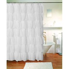 a white shower curtain in a bathroom next to a bathtub and sink with a towel on the floor