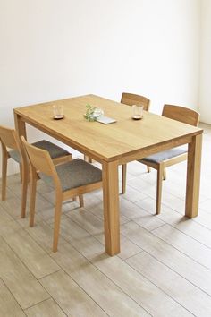 a wooden table with two chairs and a plate on it, in front of a white wall