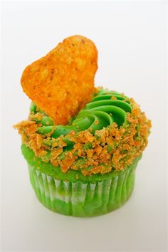 a cupcake with green frosting and orange sprinkles on the top