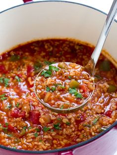 a ladle full of red beans and rice in a pot