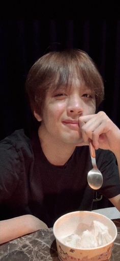 a man sitting at a table with a bowl and spoon in front of his face