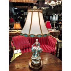 a lamp sitting on top of a wooden table next to a red couch in a store