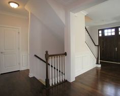 an empty living room with hard wood flooring and white walls on either side of the door