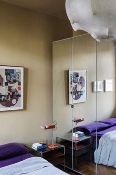 two beds in a room with mirrors on the wall and pictures on the wall above them