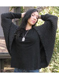 a woman standing in front of a tree with her hands on her head and arms behind her head