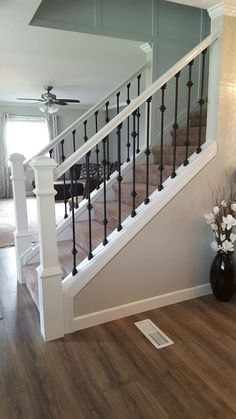 a living room filled with furniture and a stair case next to a table on top of a hard wood floor