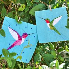 two paper hummingbirds hanging from a tree