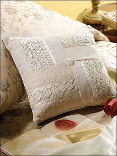 a close up of a pillow on a bed with decorative pillows and other items in the background