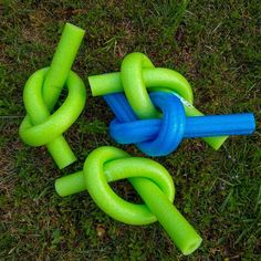 three green and blue toys laying on top of the ground in the grass with one knot tied to it's sides