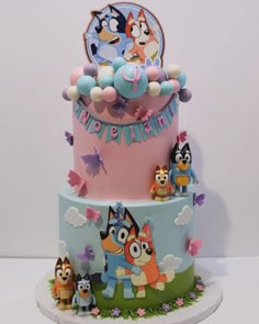 a three tiered cake with cartoon characters on it's sides and decorations around the edges