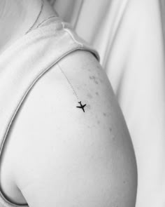 a woman with a small airplane tattoo on her arm and shoulder, in black and white