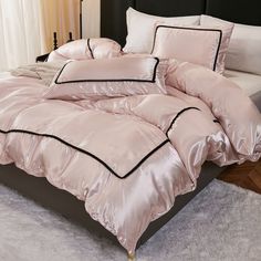 a bed with pink comforter and pillows on top of white carpeted flooring