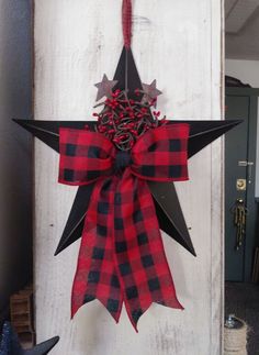 a red and black star hanging from the side of a door with a bow on it