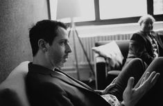 black and white photograph of two men sitting in a living room, one holding his hands out