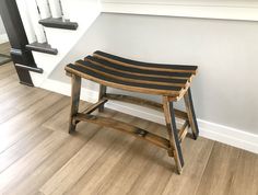 a wooden stool sitting on top of a hard wood floor next to a stair case