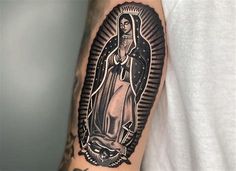 a man with a tattoo on his arm has a virgin mary in black and white