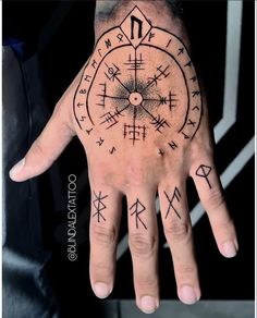 a man's hand with an ancient compass tattoo on his left palm and two arrows in the middle