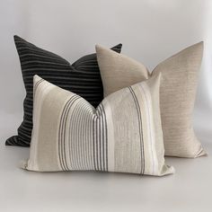 three black and white striped pillows sitting on top of each other in front of a white wall