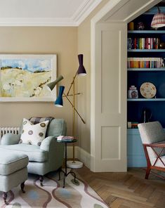 a living room filled with furniture and bookshelves next to a painting on the wall