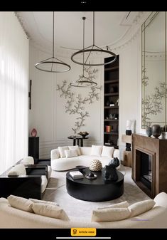 a living room filled with white furniture and lots of mirrors on the wall above it