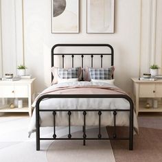 a bed sitting in a bedroom next to two framed pictures on the wall above it