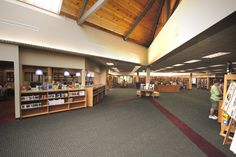 the inside of a library with people browsing and looking at books on shelves in front of them