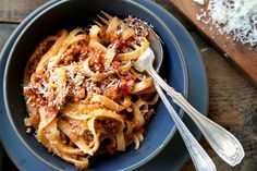 a bowl full of pasta with meat and cheese on top, ready to be eaten