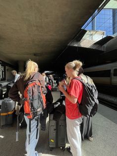 two women with backpacks are waiting at the train station for their luggage to arrive