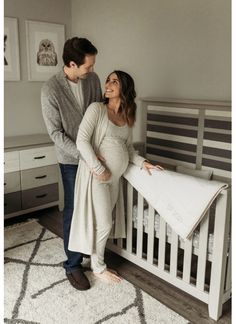 a man and woman standing next to a baby crib