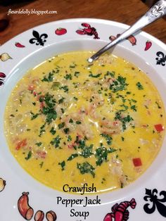 a bowl of crabfish pepper jack soup on a plate with a spoon in it