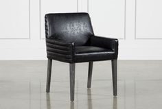 a black leather chair sitting on top of a hard wood floor next to a white wall