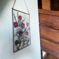 a painting hanging on the wall with flowers in it