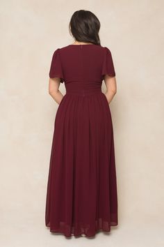 the back of a woman wearing a maroon dress with short sleeves and pleaed skirt