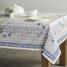 a white table with blue and yellow flowers on it, next to a brick wall