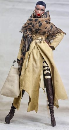 a woman in a trench coat and boots holding a handbag