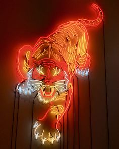 a neon sign with a tiger on it's face in front of a wall