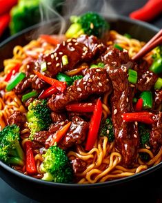 beef and broccoli stir fry in a black bowl with chopsticks on the side