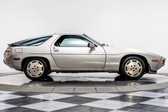 a silver car parked on top of a black and white checkered floor