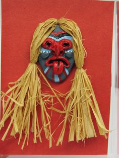 a mask made out of straw with red and blue paint on it