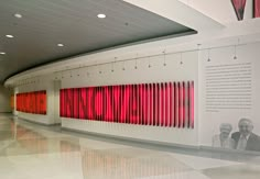 an art gallery with red and white lines on the wall next to two men in suits