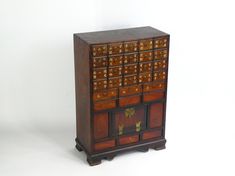 Amazing antique wooden Asian apothecary with 25 drawers with Chinese carvings and small brass rings and a small door on the bottom decorated by brass fittings.  Made out of solid wood, this spice chest is definitely and eye catcher and useful at the same time. In good antique condition with scratches and traces of use overall. There is also some paint/stains on one side of the cabinet. Please see pictures for all details. Measurements: Height: 29.9 inches (76 cm) Length (largest part): 21 inches Asian Cabinet, Medicine Chest, Small Door, Medicine Cabinets, Brass Rings, Spice Storage, Paint Stains, Small Doors, Brass Fittings