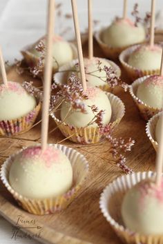 some white chocolates with pink sprinkles are on a wooden platter