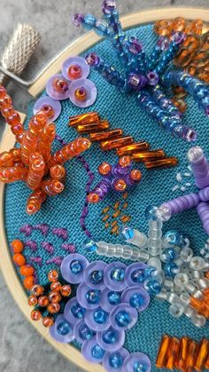 a close up of a embroidery with beads and other items on the table next to it