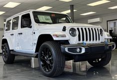 a white jeep is parked in a showroom