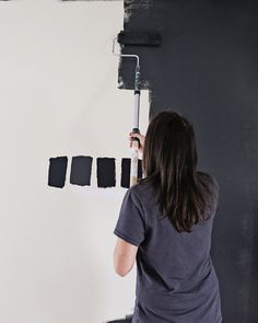 a woman is painting the wall with black paint