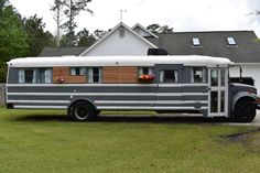 an old school bus is parked in front of a house with flowers on the windows