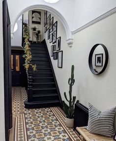 an entryway with stairs and pictures on the wall, potted cactus next to it