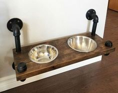 two stainless steel bowls are on a wooden shelf with black pipe handles and knobs