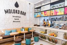 the interior of a cafe with colorful signs on the wall and wooden stools in front of it