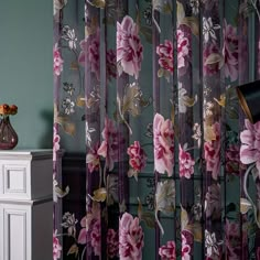 the curtains are decorated with pink flowers and gold trimmings, along with a black lamp